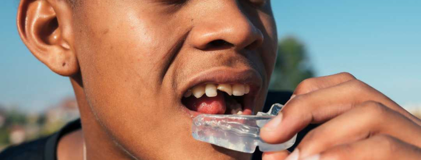 Athlete putting on dental protection for athletes.