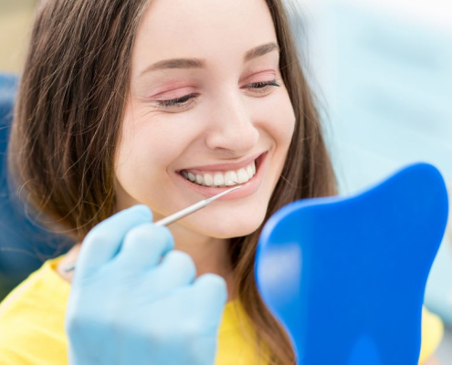 A smiling pregnant woman receiving prenatal dental care during a checkup at a dentist's office.