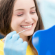 A smiling pregnant woman receiving prenatal dental care during a checkup at a dentist's office.