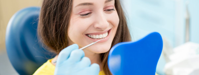 A smiling pregnant woman receiving prenatal dental care during a checkup at a dentist's office.